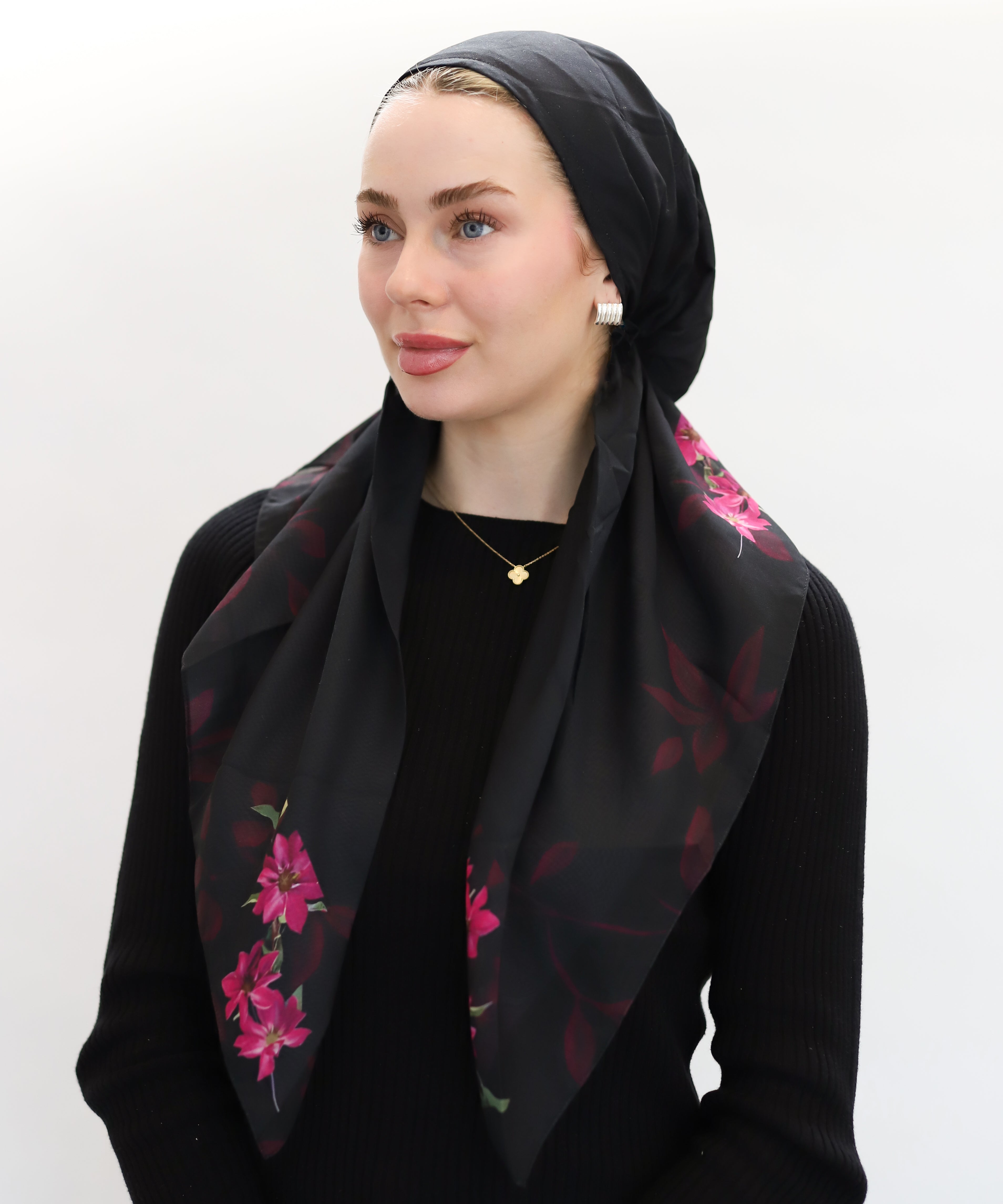 Woman wearing a black pre-tie adjustable from TUK with pink floral patterns on a white background.